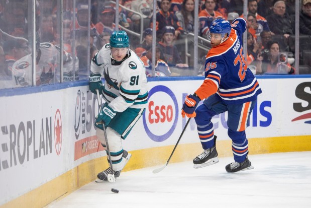 San Jose Sharks' Carl Grundstrom (91) battles for the puck with Edmonton Oilers' Darnell Nurse (25) during first-period NHL hockey game action in Edmonton, Alberta, Friday, April 11, 2025. (Amber Bracken/The Canadian Press via AP)