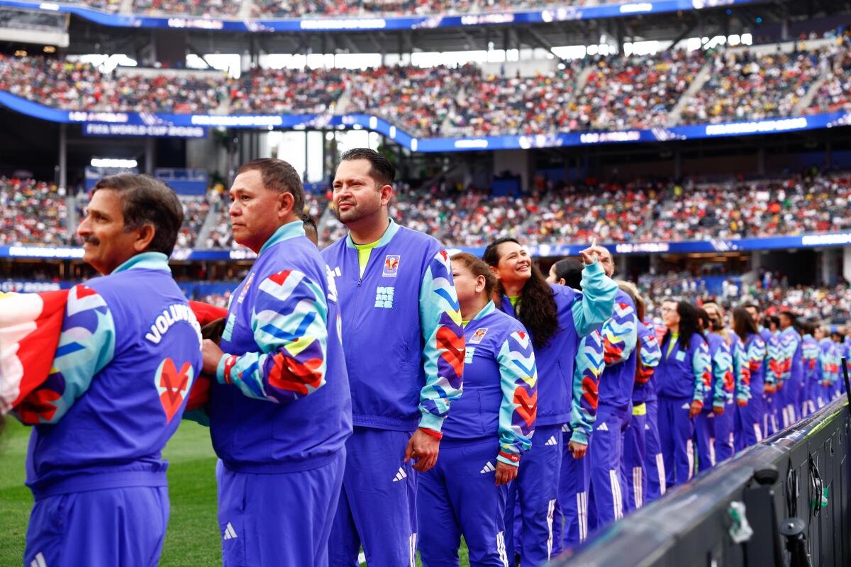 Volunteers line up to prepare to display the Canadian Flag before a World Cup game.