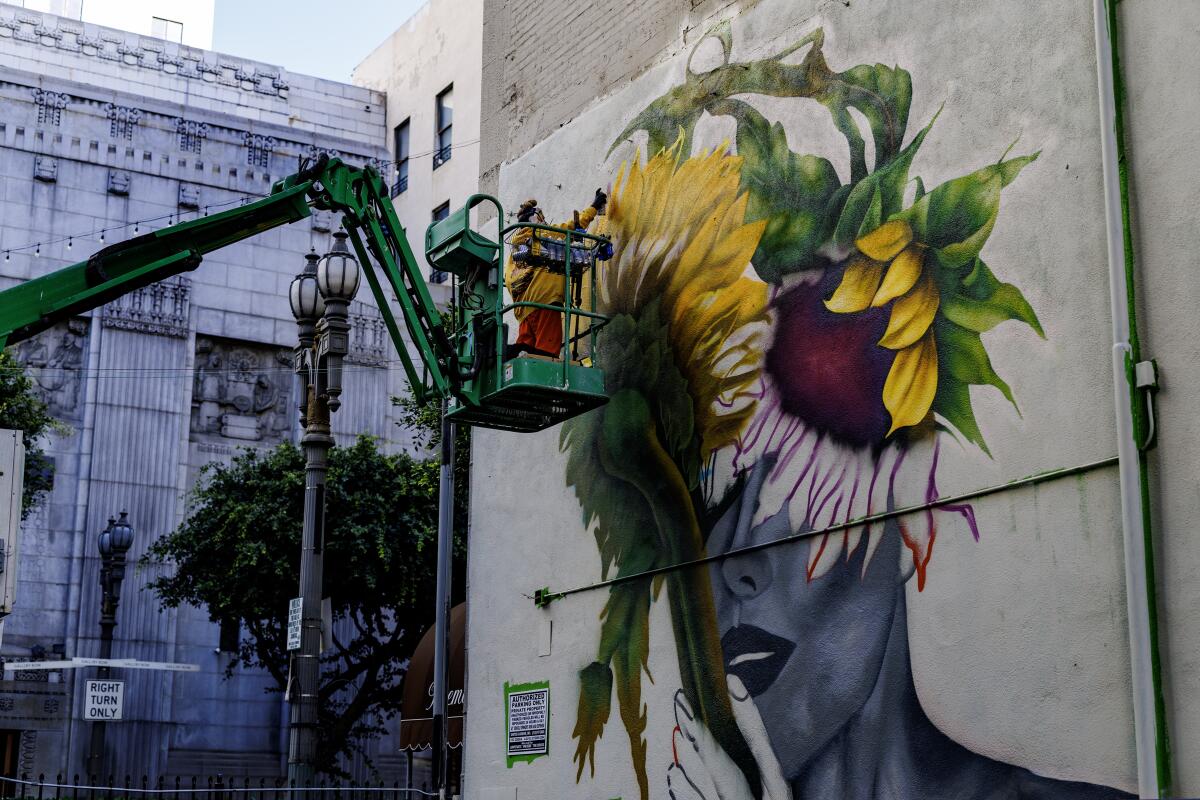A local artist uses spray paint to work on her large mural on the side of the Premier Towers building off Spring Street.