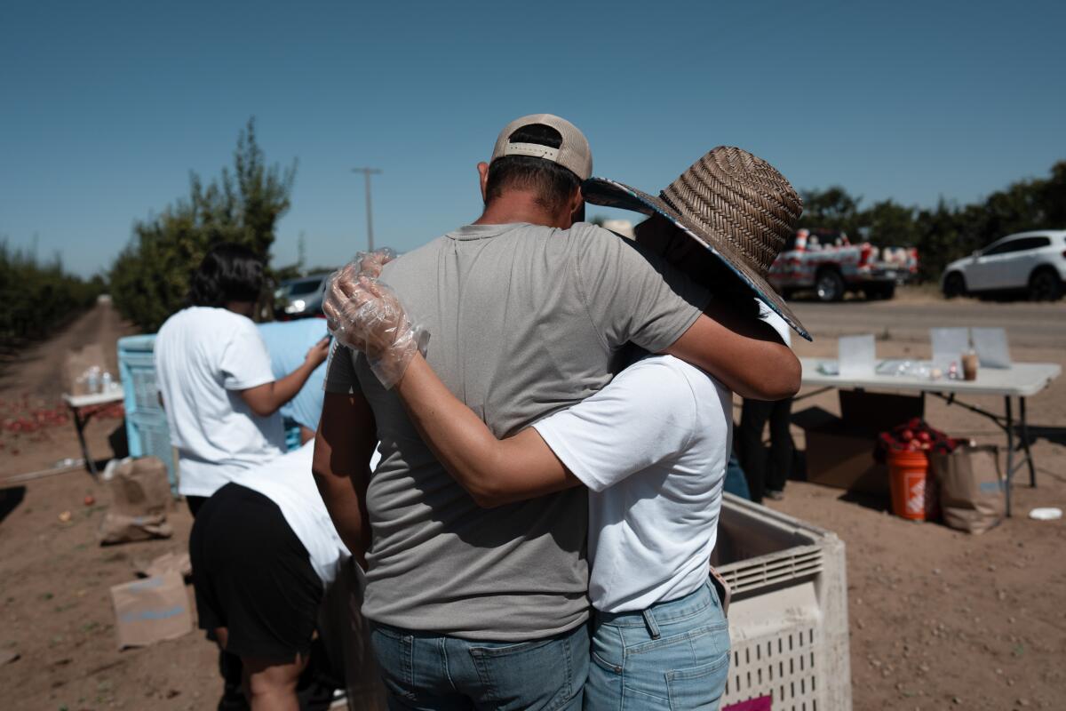 Cesar Mora, left, and his wife, Juliana, hug after a free nectarine giveaway.