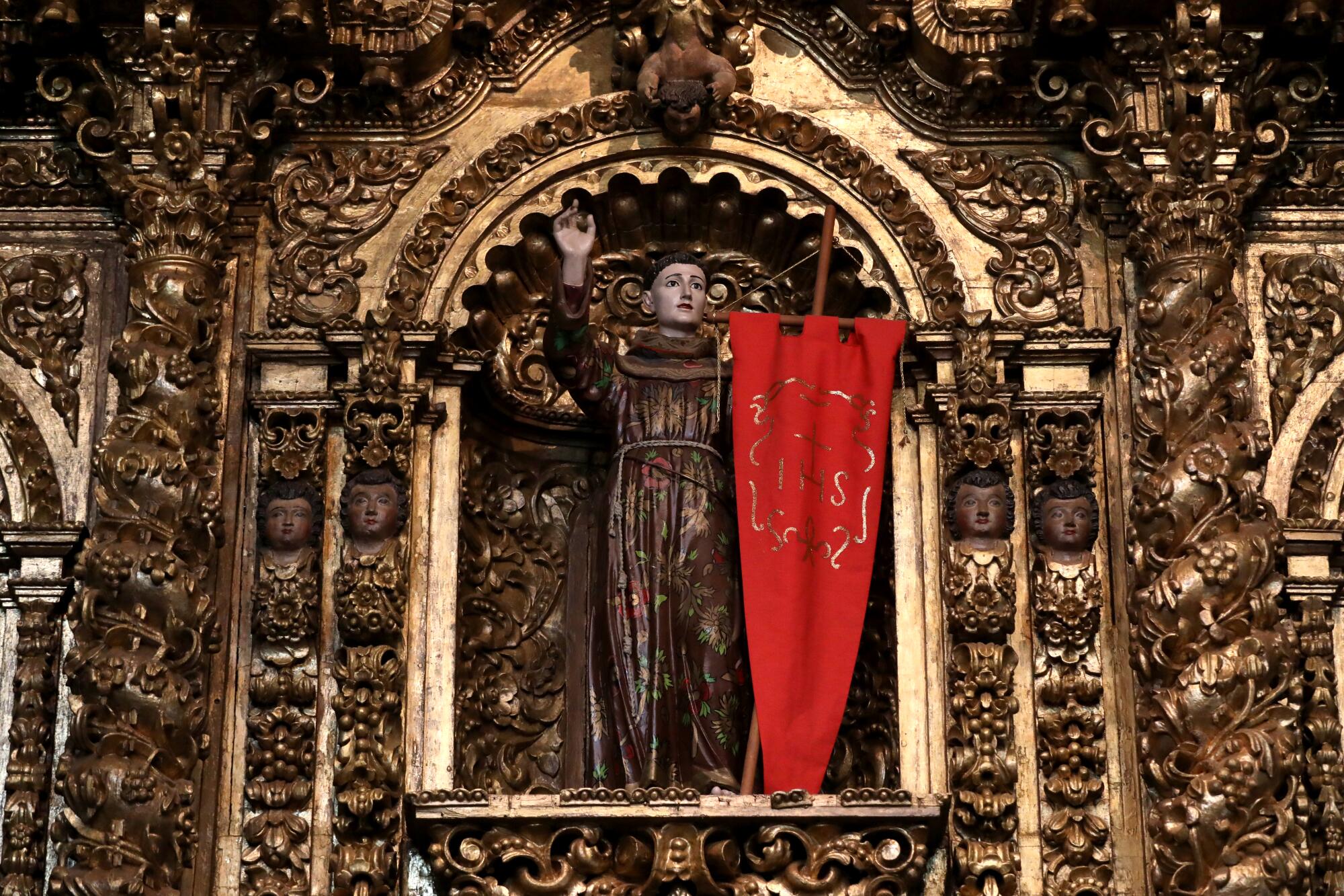 A statue of St. John of Capistrano surrounded by gold painted carvings in a chapel