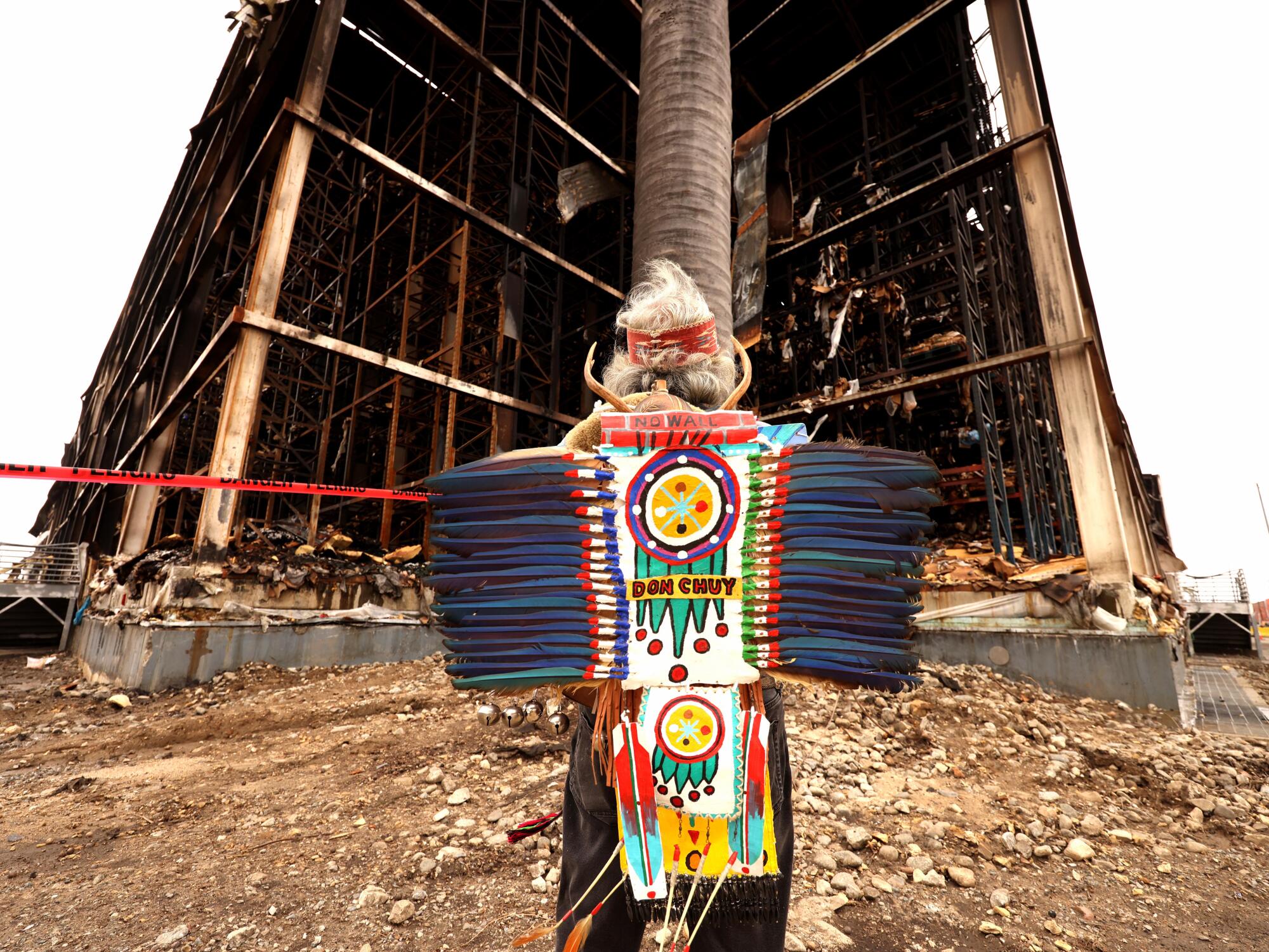 A medicine man prays to the four elements at the site of the Lineage Logistics warehouse fire.