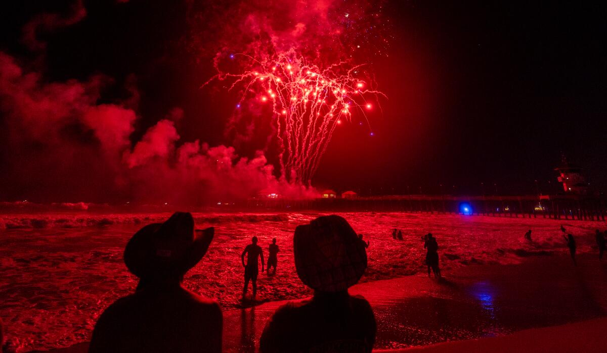 Fireworks light up the sky over the ocean and pier in Huntington Beach.
