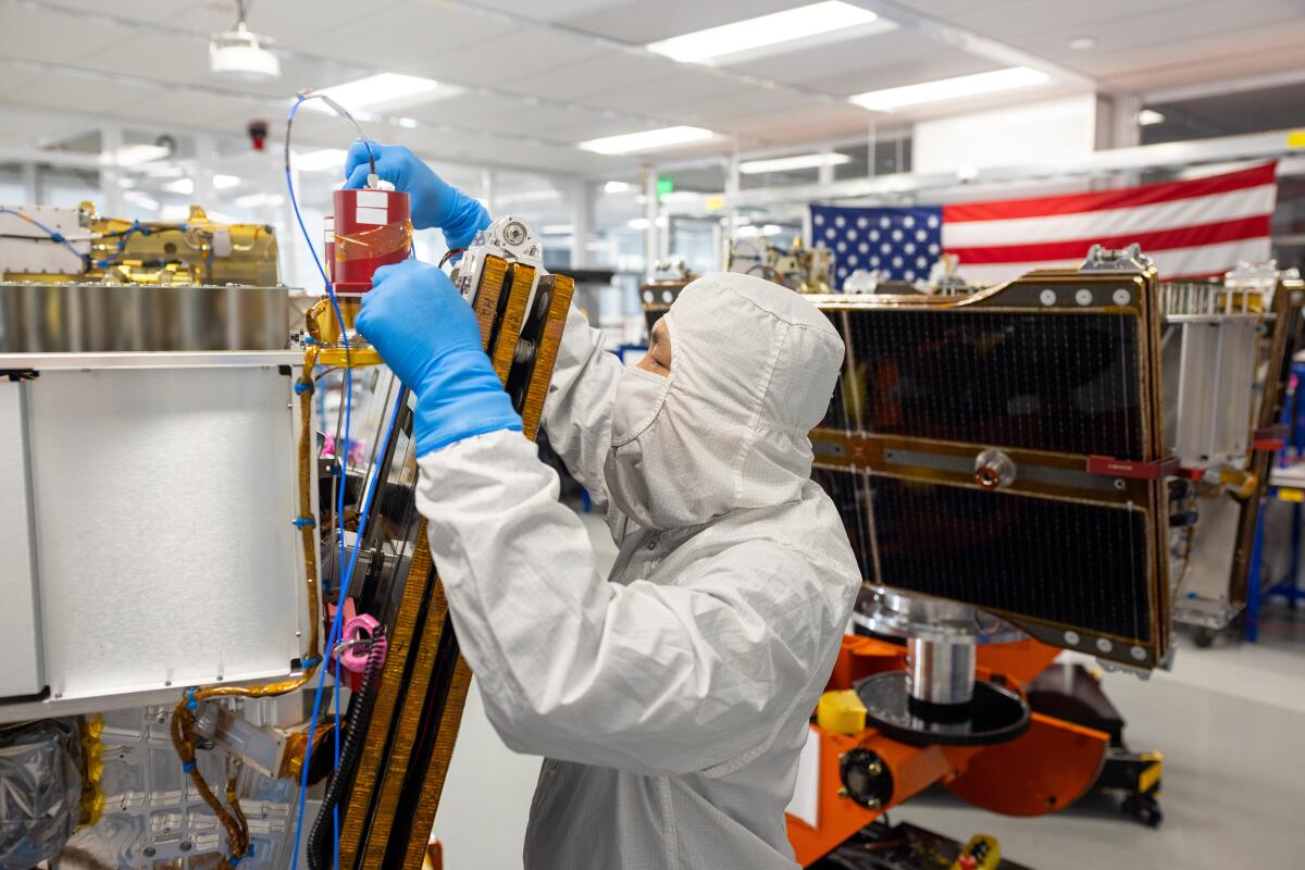 A worker at Mountain View-based Muon Space puts the final touches on a wildfire-detection satellite.