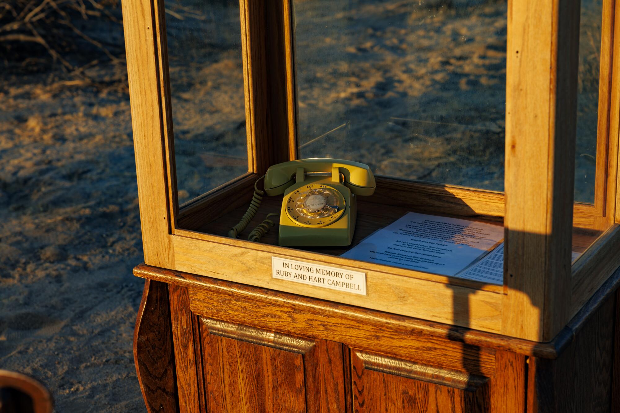 An old rotary telephone sits inside a custom phone booth.