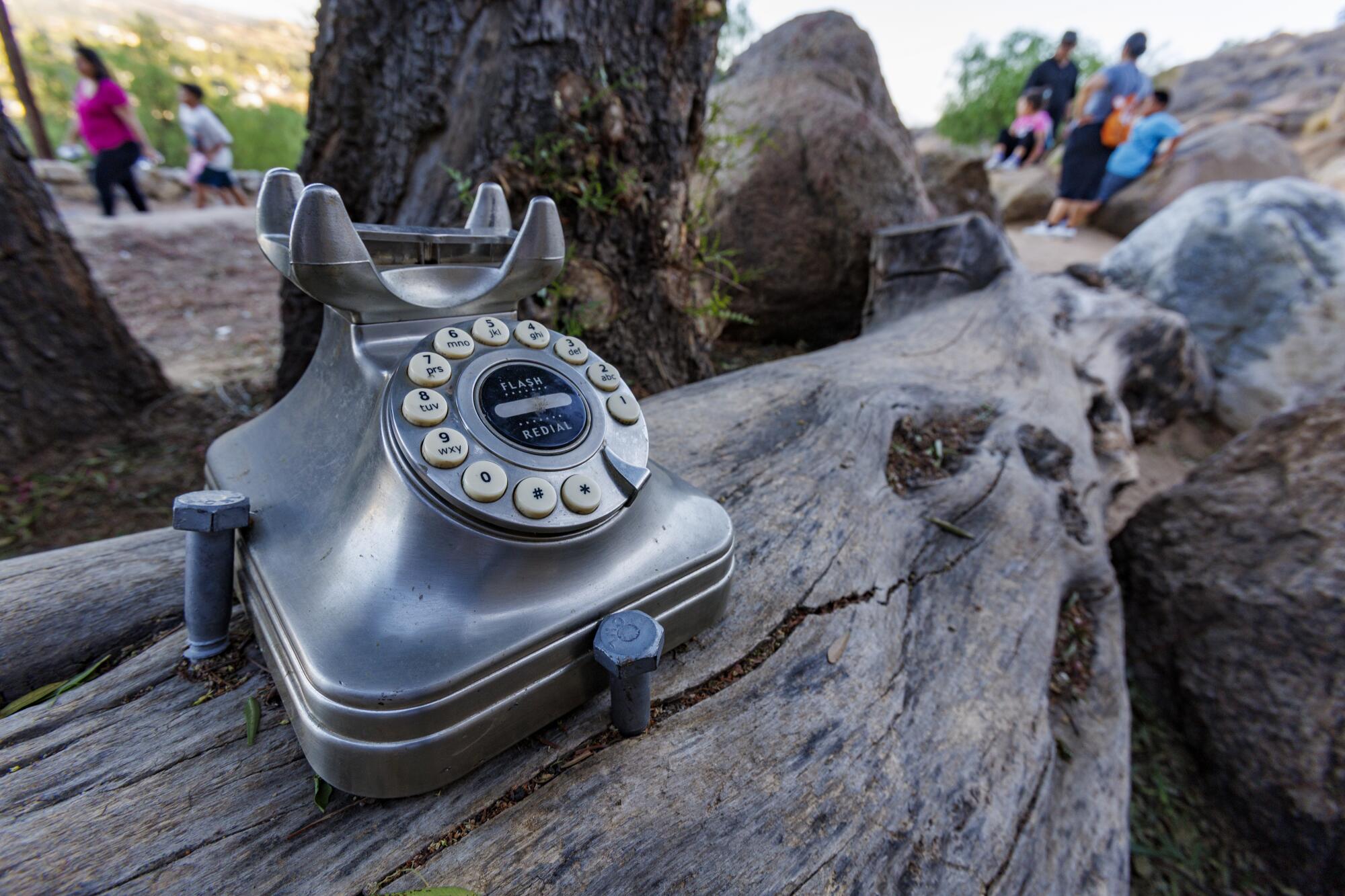 Hikers pass a wind phone that has been vandalized.