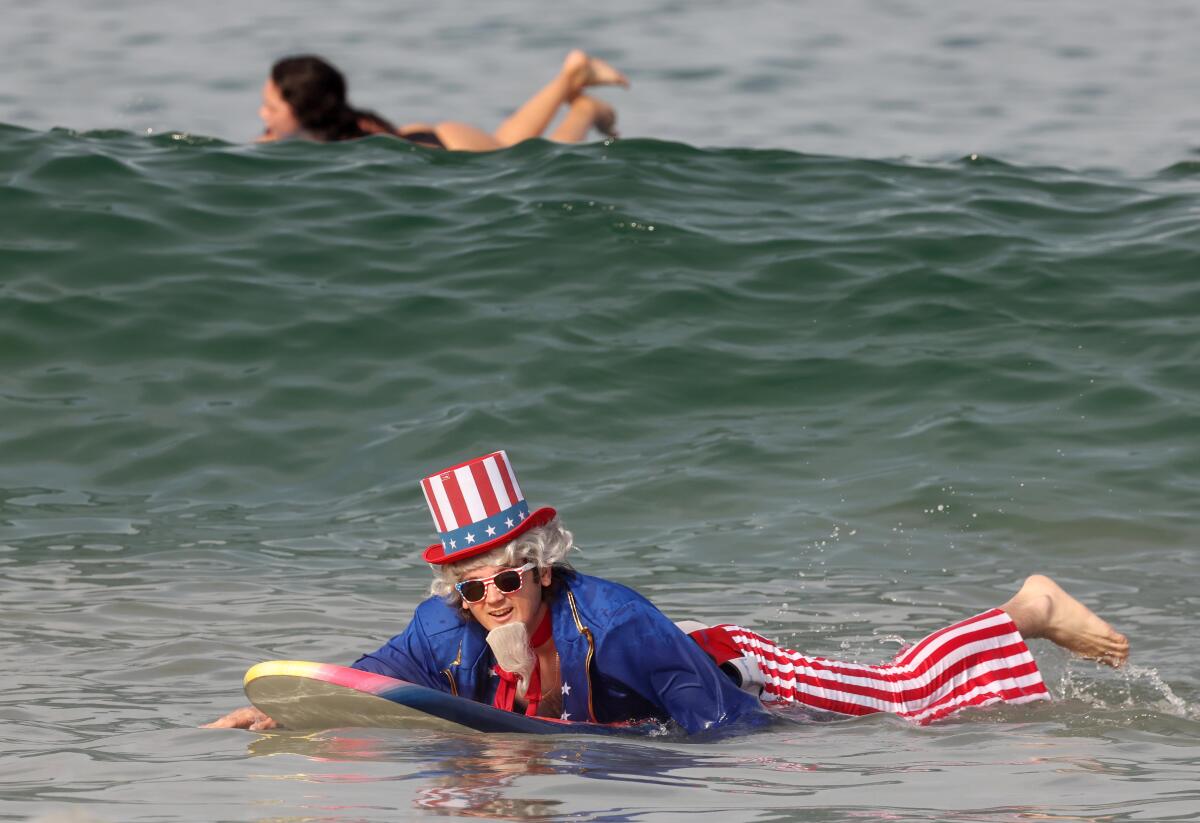 A man dressed as Uncle Sam paddles on his surf board in the ocean at Hermosa Beach 