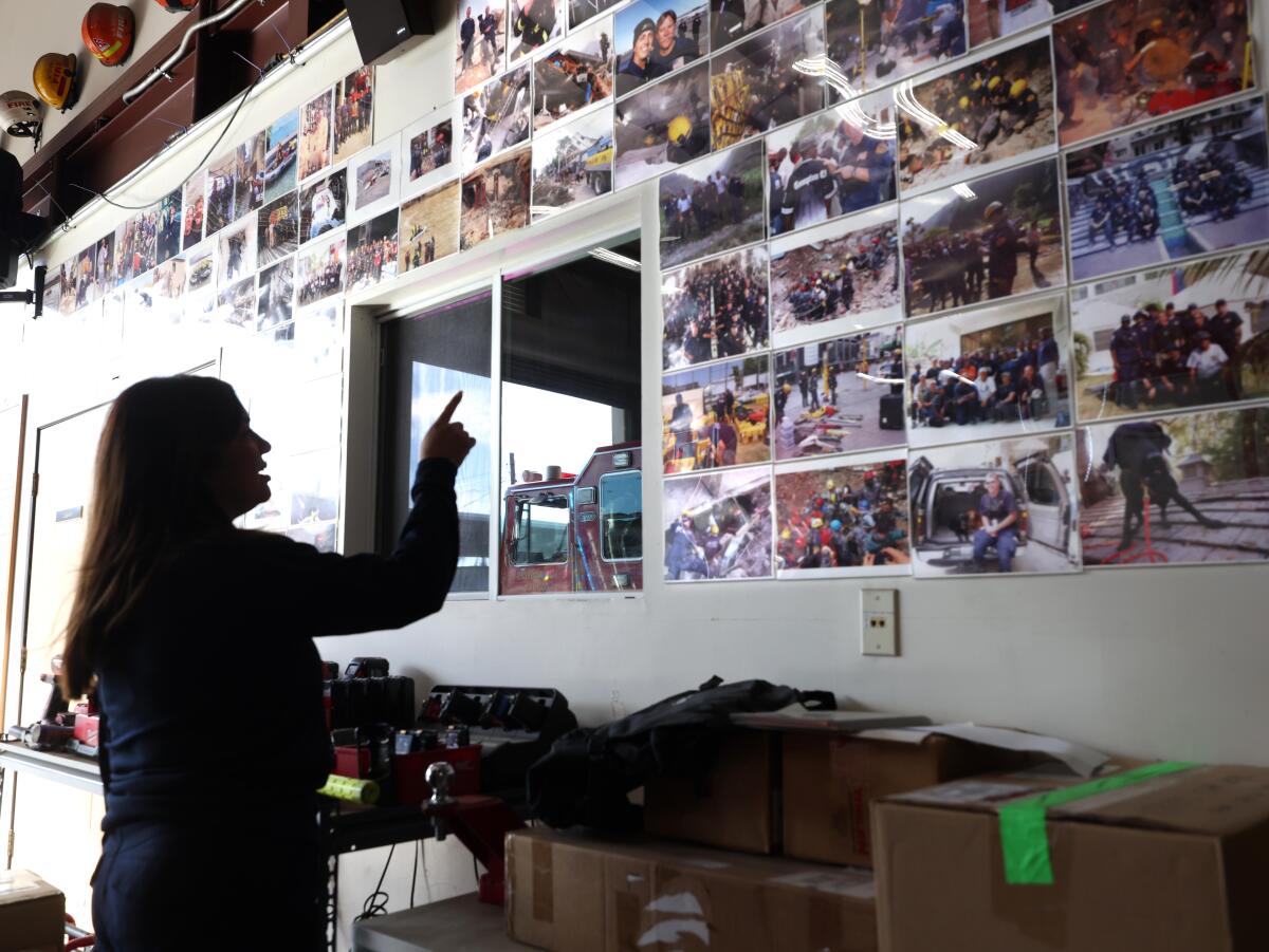 A woman points to a wall full of photos.