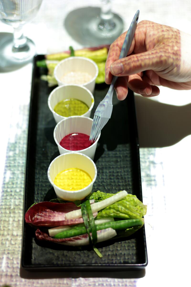 A guest uses a silicon brush to apply sauces onto an entree, a nod to abstractionist Jackson Pollock.