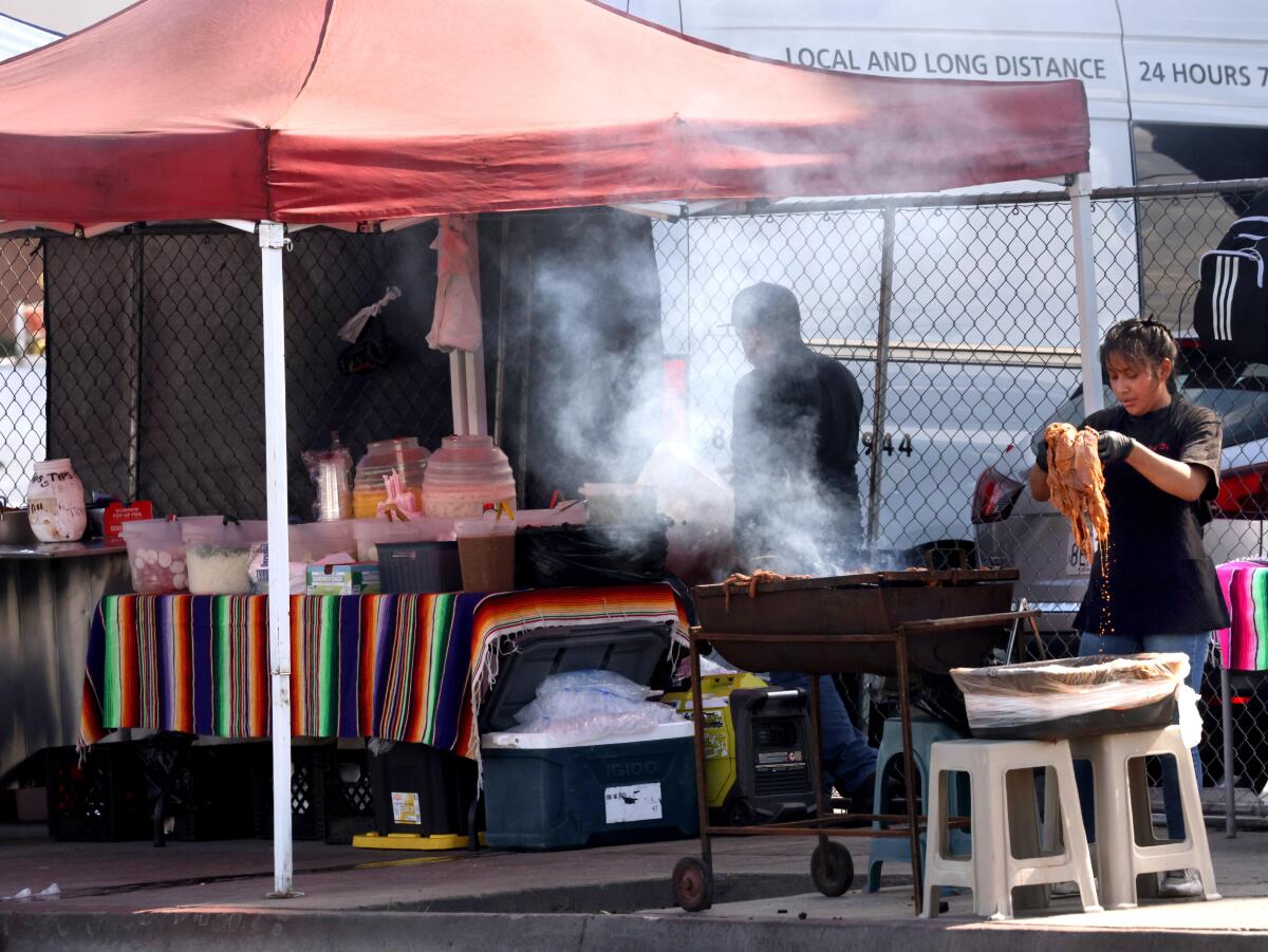 Ricos Tacos Naomi employees grill meats at their taco stand