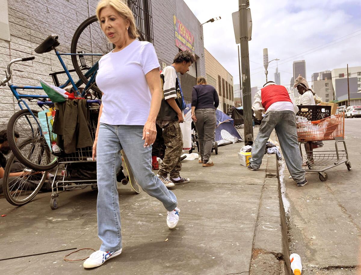 A woman walks past homeless and others residents of Skid Row in downtown Los Angeles