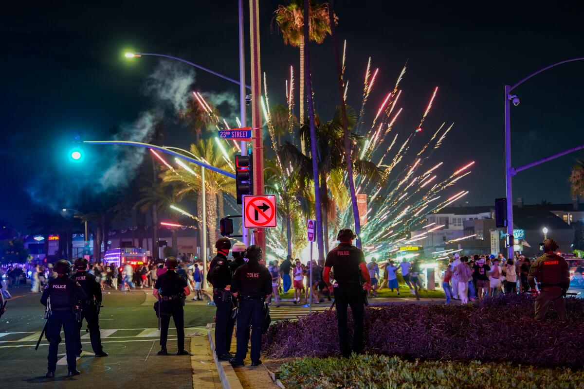 Newport Beach police Saturday look on as revelers light illegal fireworks. 