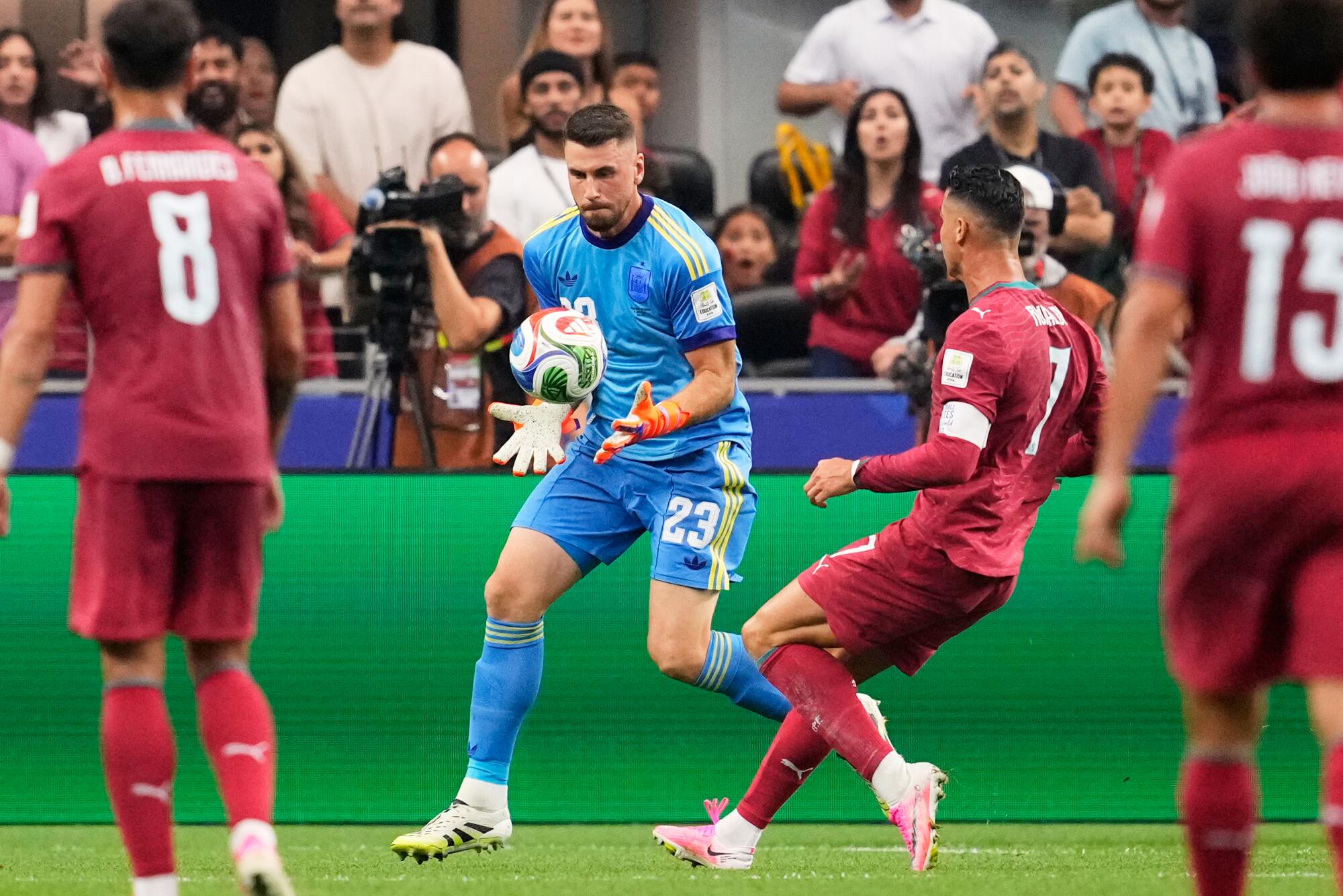 Spain goalkeeper Unai Simon catches the ball in front of Portugal's Cristiano Ronaldo.