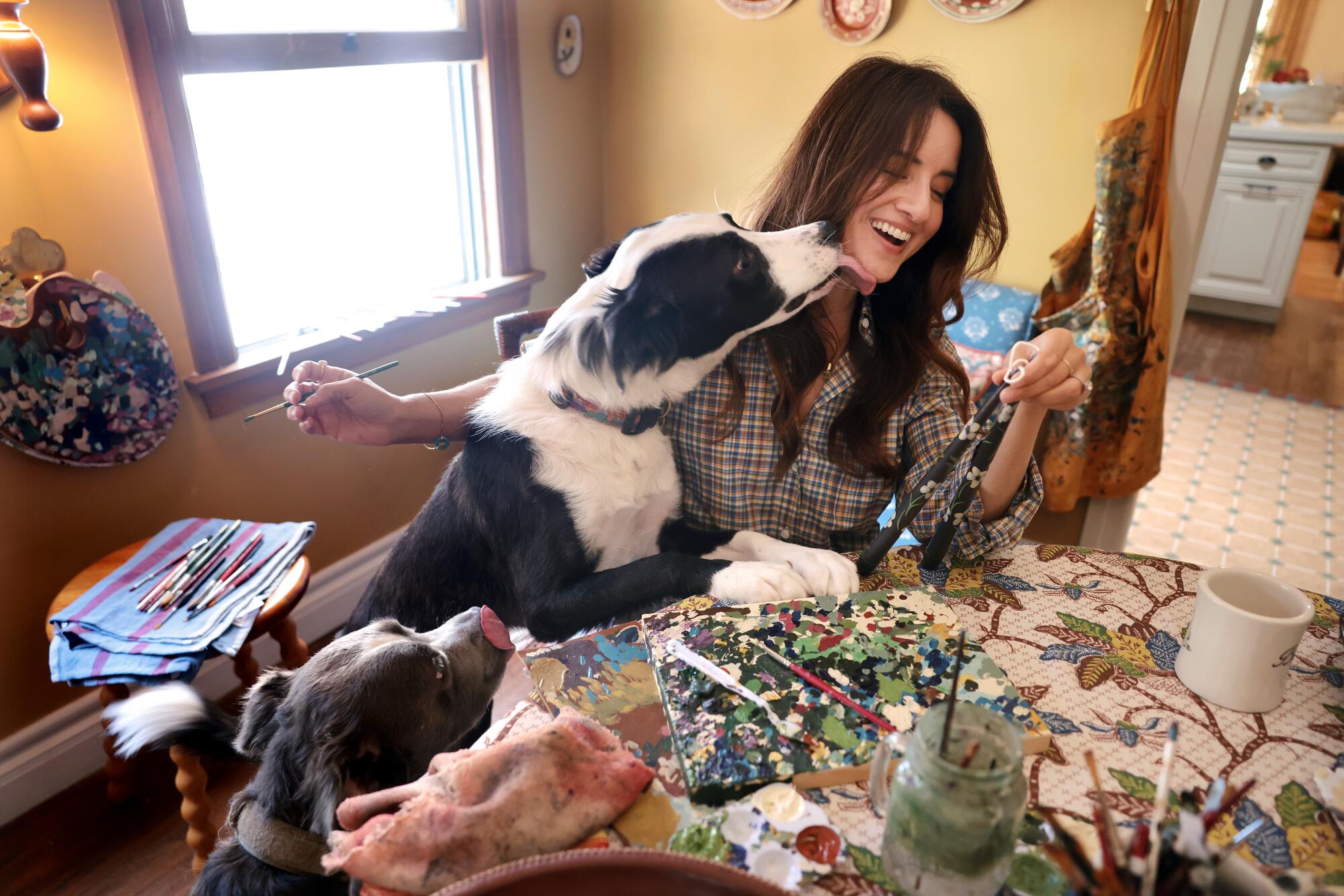 Saleh gets a surprise kiss from her dog while painting candles in her dining room. 