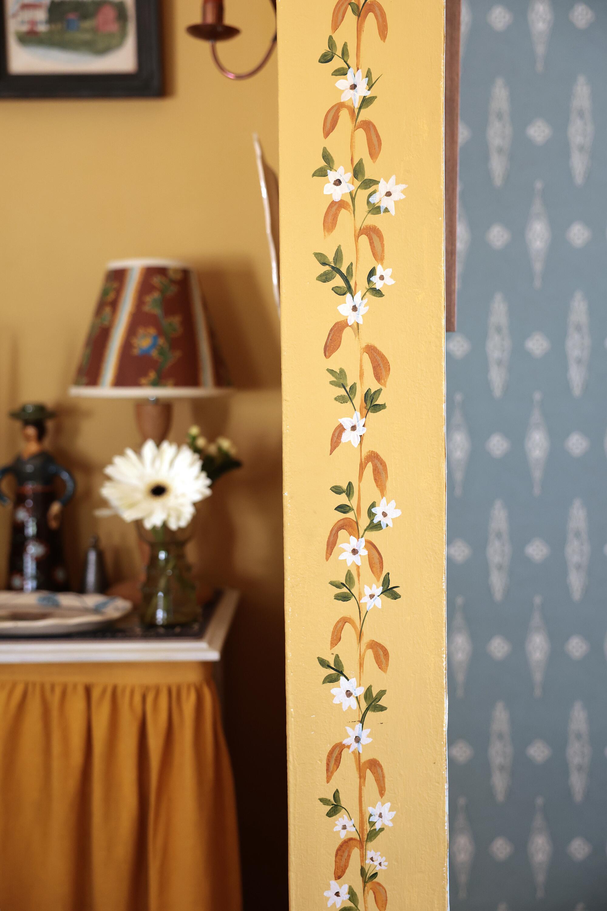 White flowers painted on a yellow arch inside Esme Saleh's home.