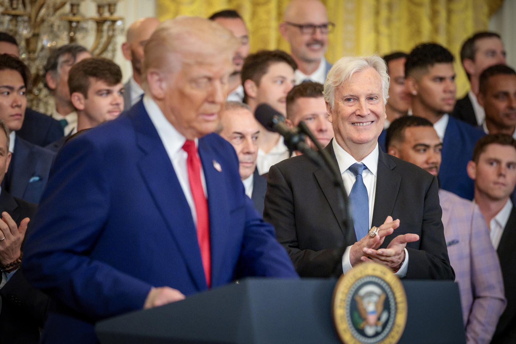 Dodgers owner Mark Walter, right, smiles while listing to President Trump speak.