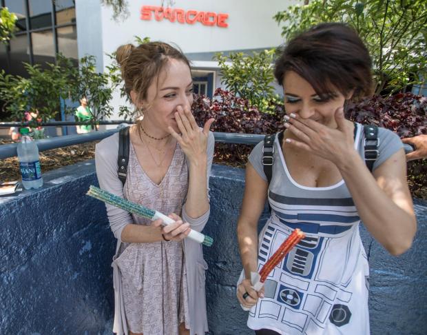 Kelsey Harold, dressed as Rey, left, and Megan Siana, R2D2, share a laugh after taking a bite of their lightsaber churros at Disneyland in Anaheim, California, on Thursday, May 4, 2017. The pair were celebrating Star Wars day - May the Fourth. (Photo by Jeff Gritchen, Orange County Register/SCNG)