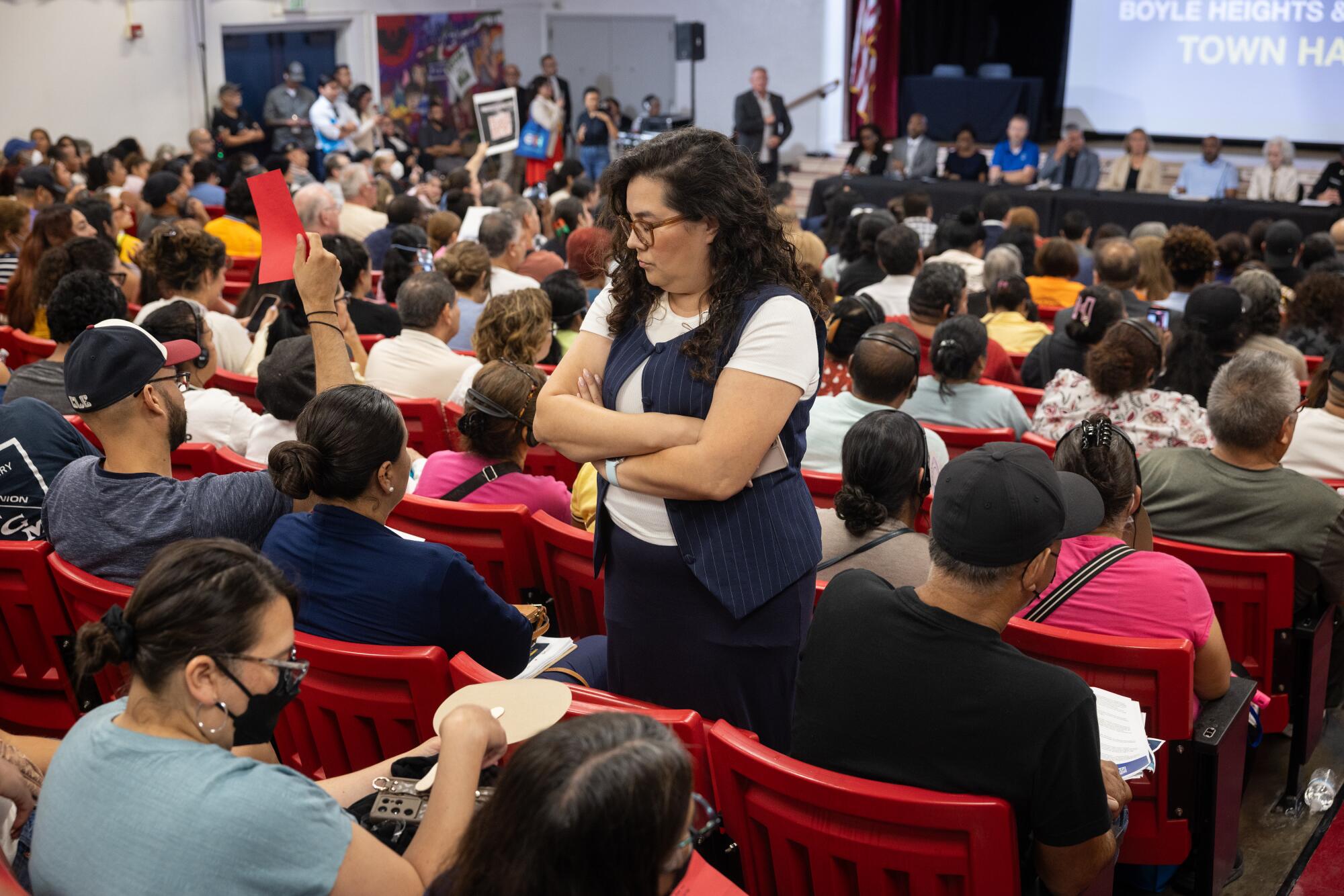 A member of the audience turns her back to the stage in sign of protest during the community meeting.
