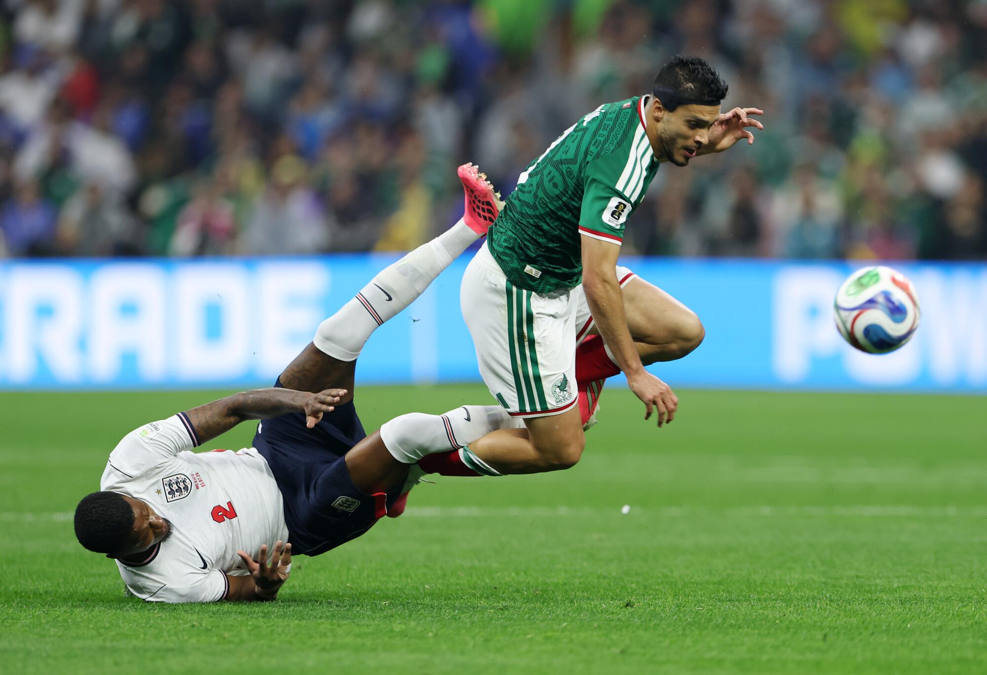 Mexico's Raúl Jiménez gets tangled with England's Ezri Konsa while going for the ball during a World Cup match.