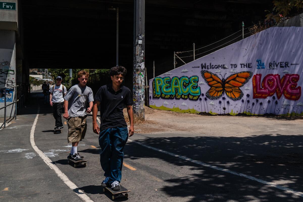 Skateboarders roll along a graffitied bike path.