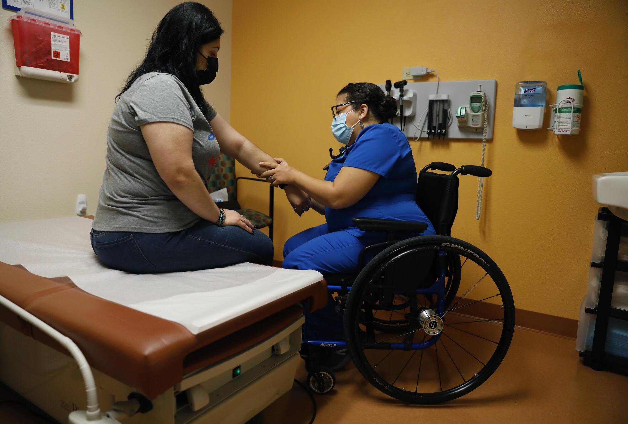 Physician Marie Flores, right, examines patient Karla Olguin, 35, left, at an AltaMed clinic.