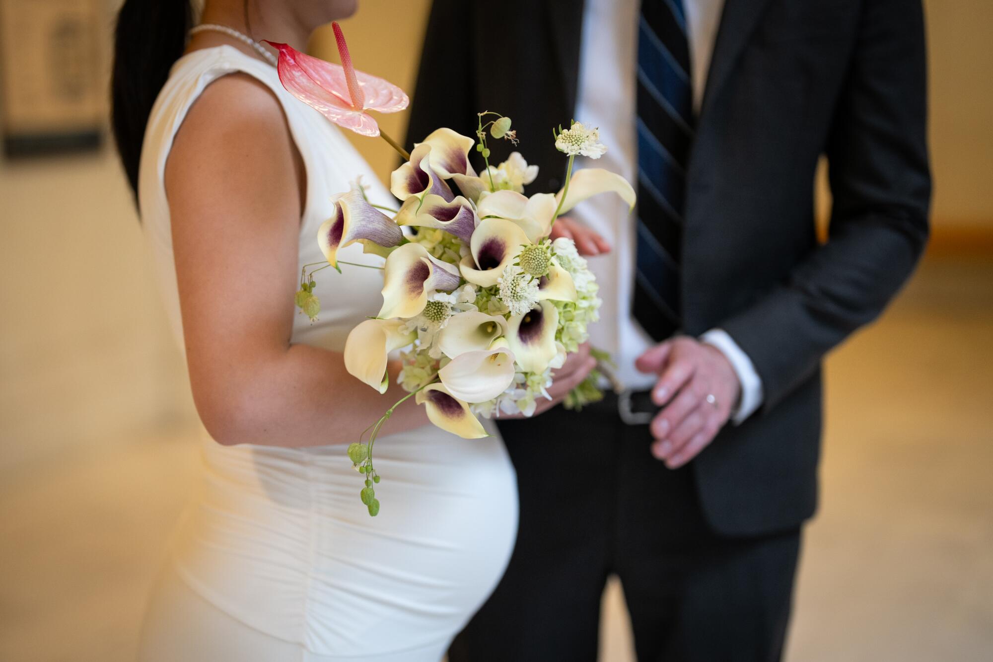 A close-up of the midsections of a groom and a pregnant bride.
