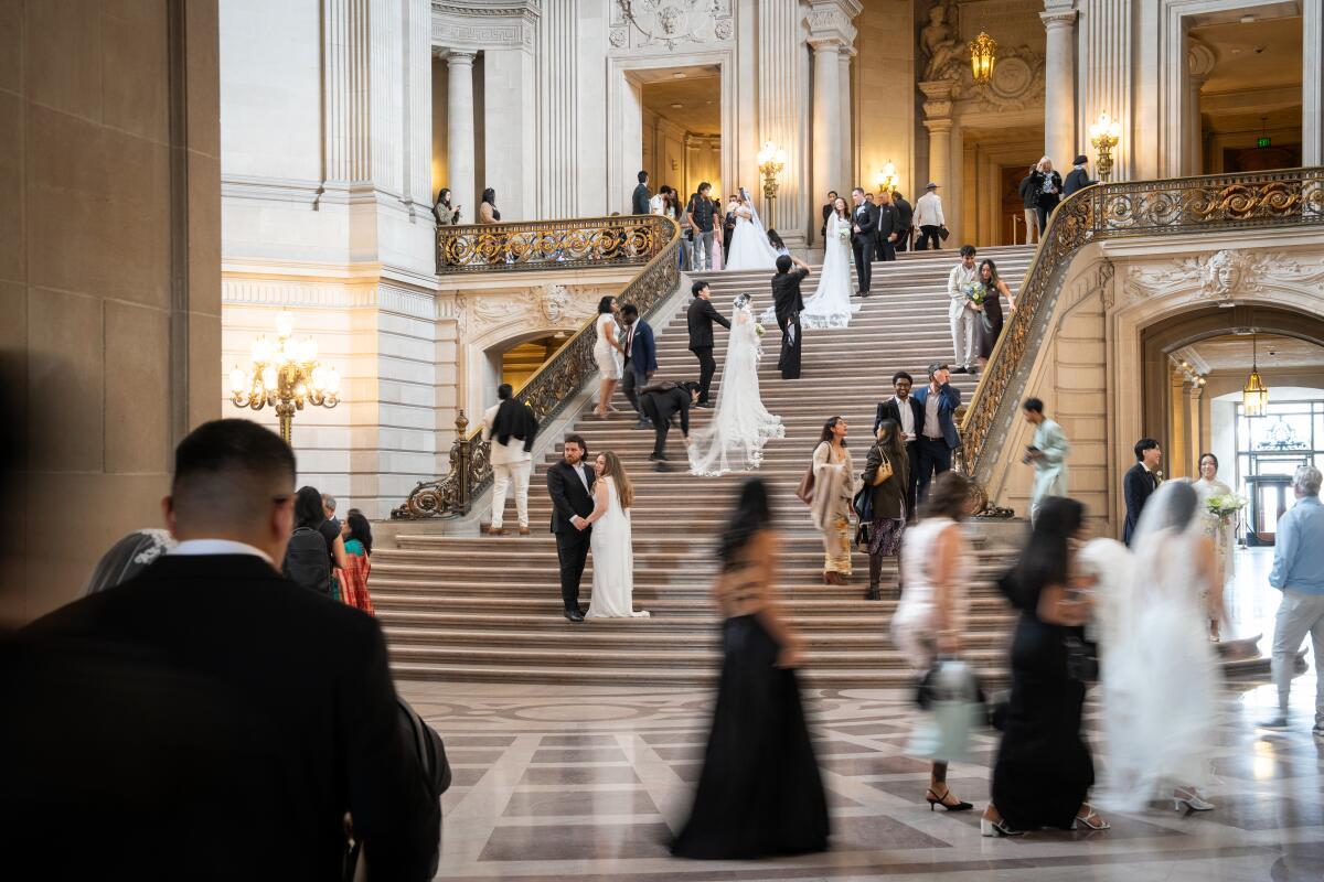 Newlywed couples and guests walk through San Francisco City Hall during its busiest wedding day of the year 