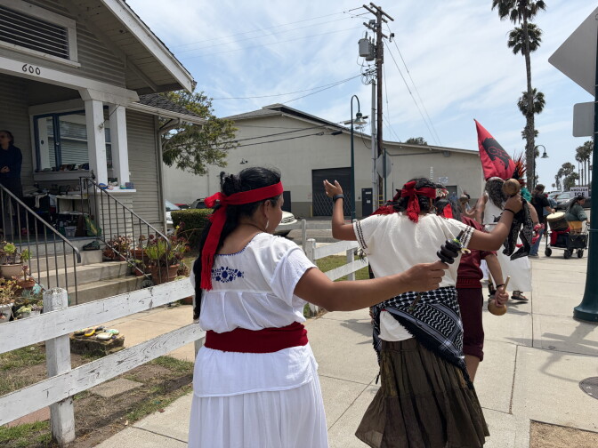 People are seen walking away from the camera and wearing red headbands. They are walking along a sidewalk.