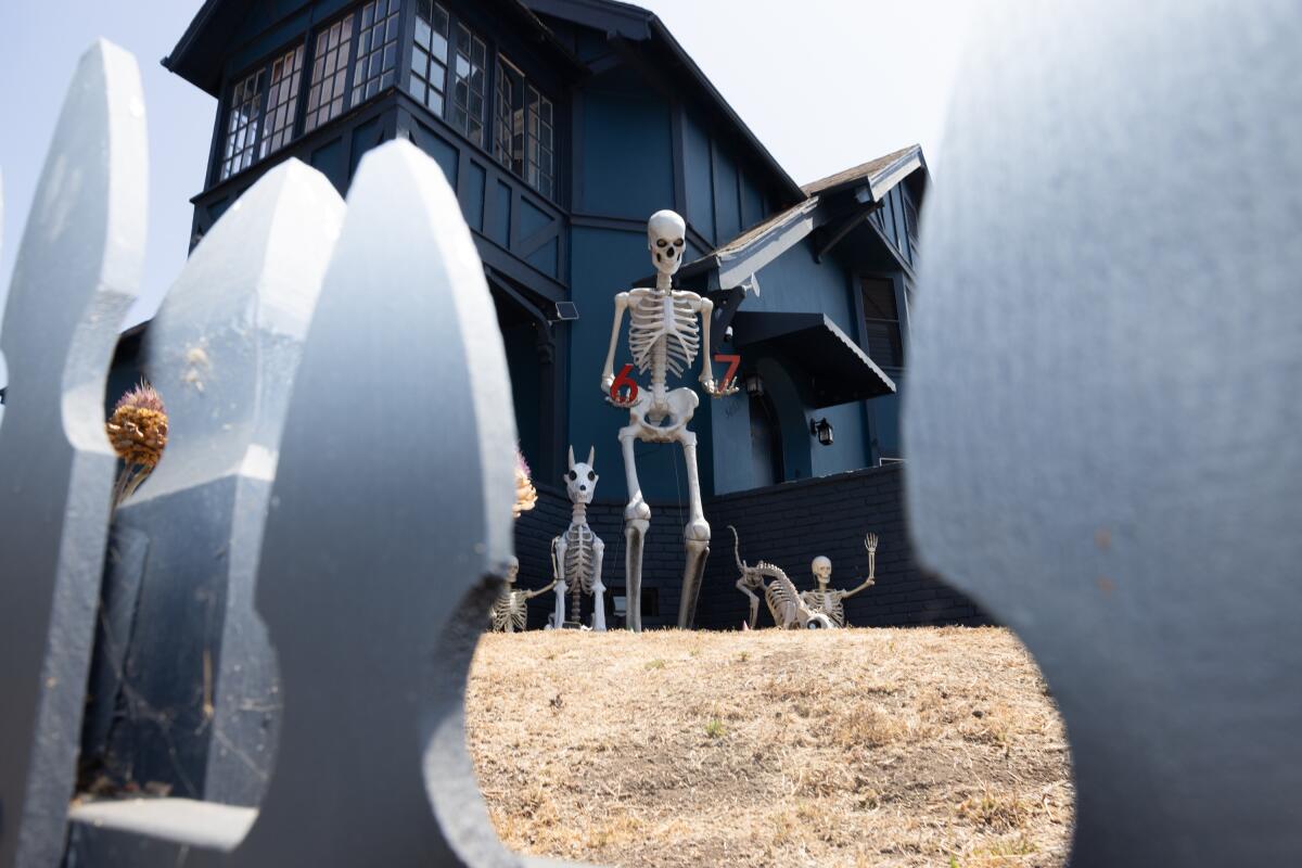 Giant skeletons, holding the numbers 6 and 7, sit in the yard of a home on N. Normandie Ave. in Los Angeles.