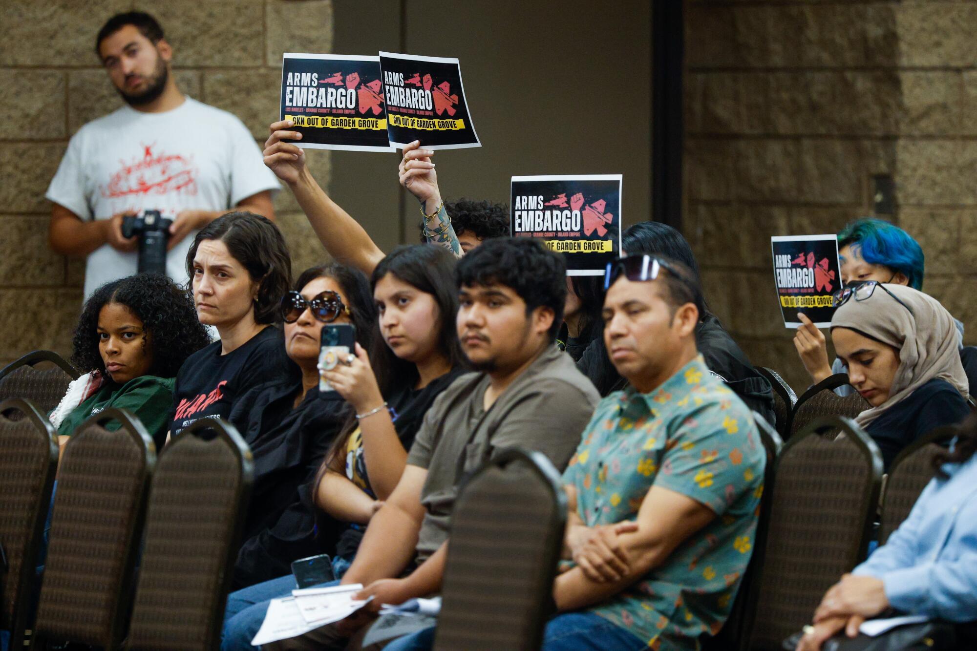Attendees hold up signs during a Garden Grove community meeting about the chemical leak at  GKN Aerospace on May 26, 2026. 