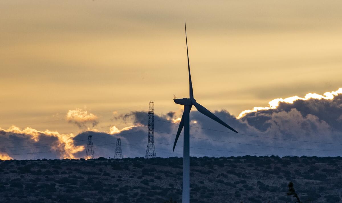 Dusk settles over wind turbines in the desert landscape in Rosamond