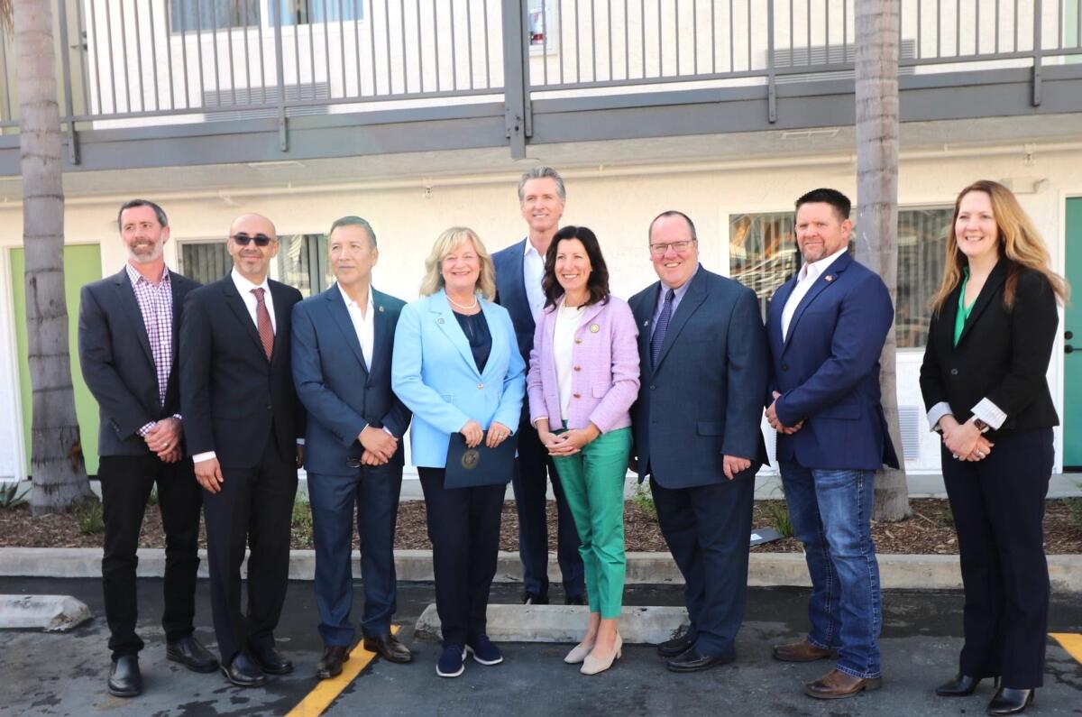 Gov. Gavin Newsom, back, with officials from Orange County, Costa Mesa and Newport Beach at the opening of a housing site.