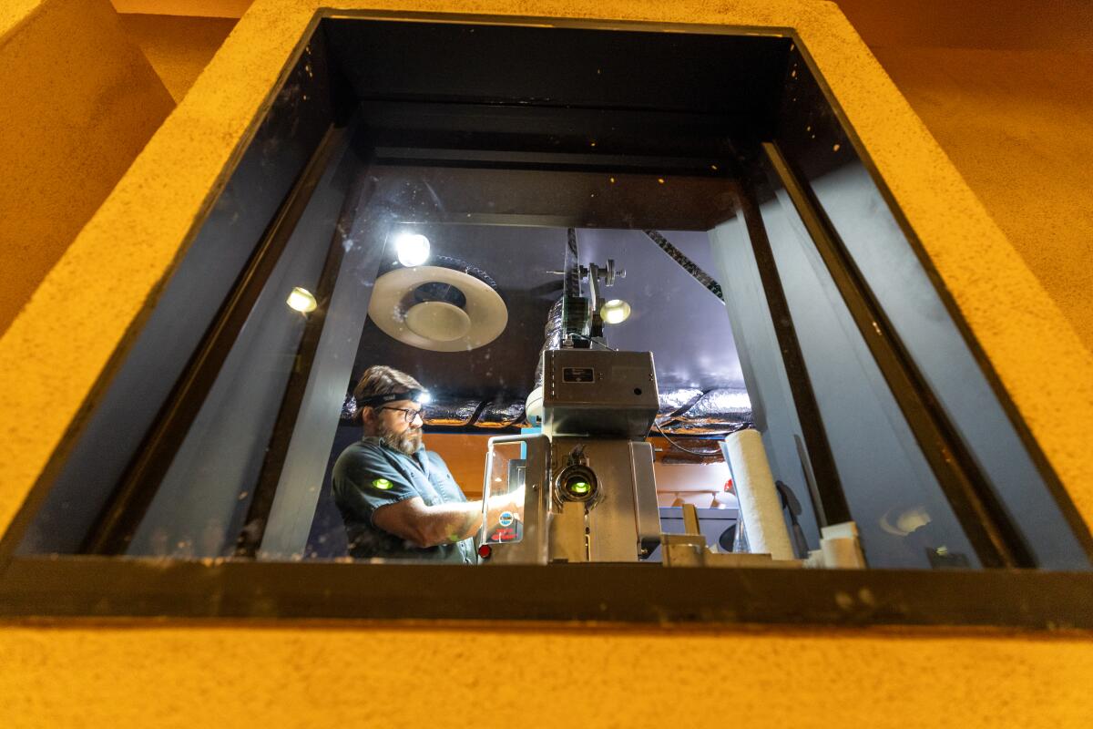 A man loads film into a projector.