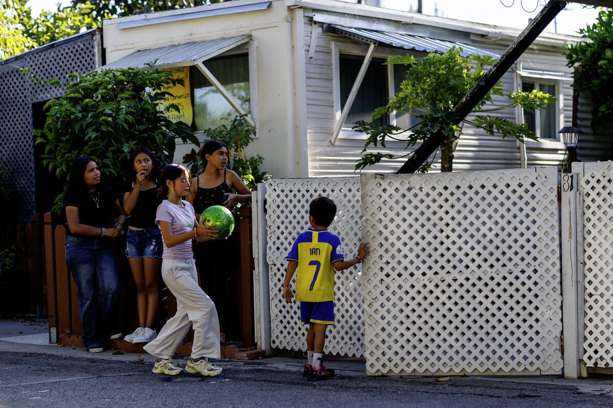 Ian Herrera, 6, gives his soccer ball to his sister Genesis,12, before walking into his mobile home