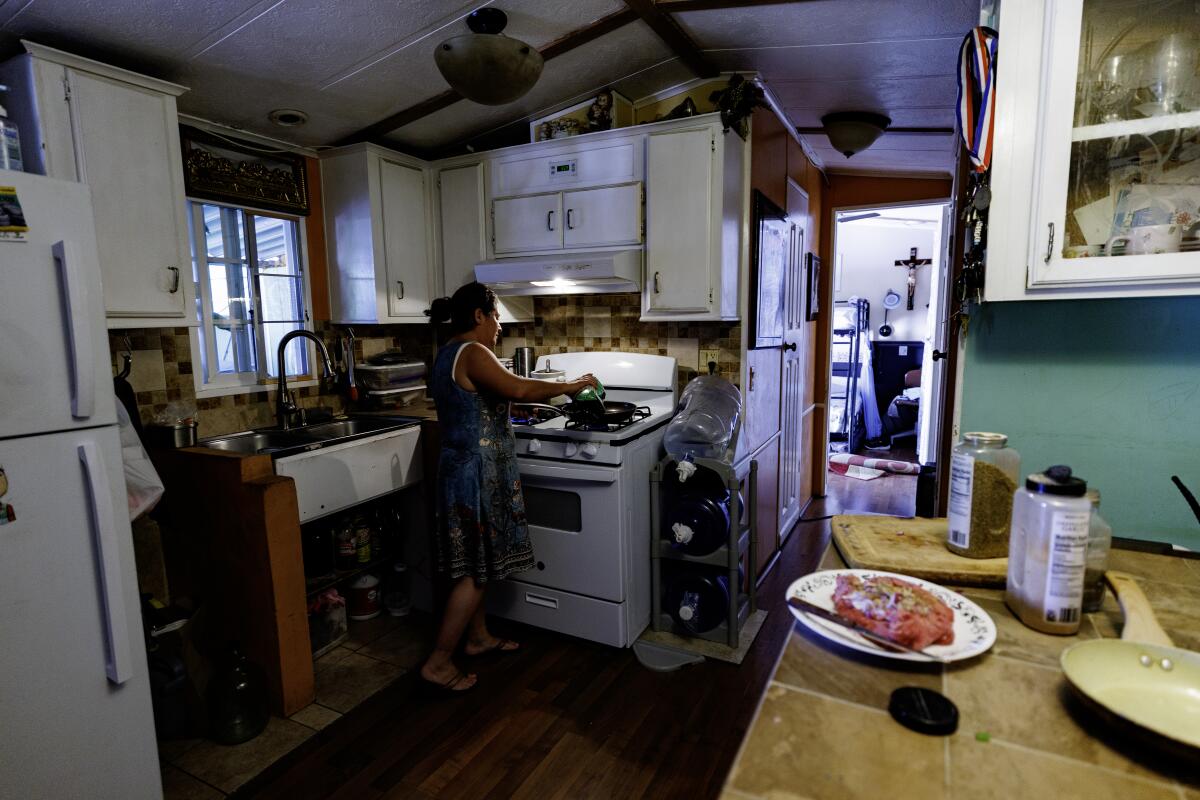 Maribel Herrera of Bell prepares dinner for her family of four inside her mobile home 