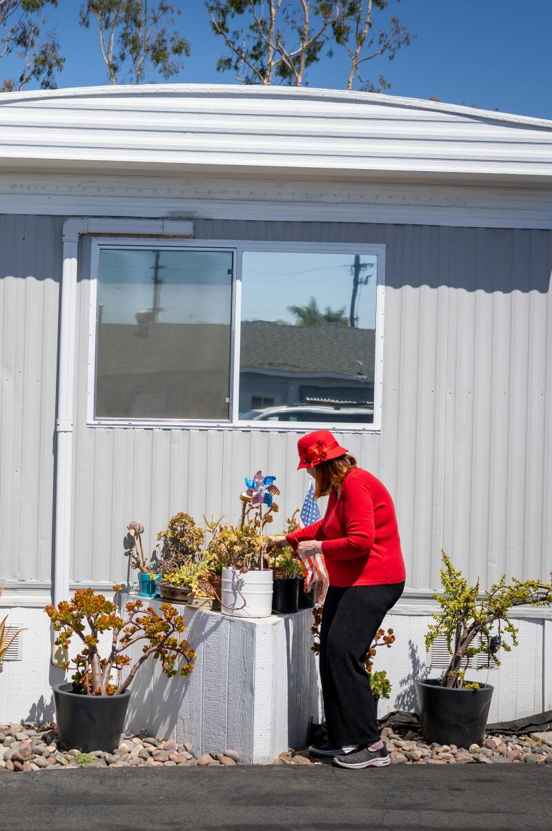 a resident adjusts decorations in front of her single wide mobile home