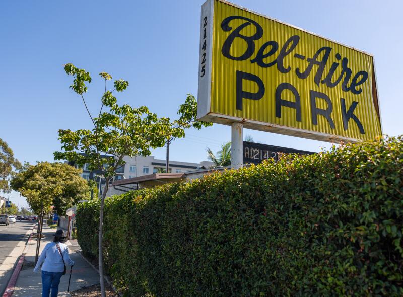 A person walks by the sign at Bel-Aire Mobile Home Park