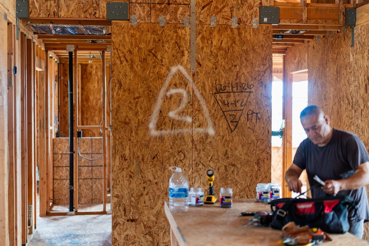 A contractor cleans up for the day after working on the half-built home of the Singh family.