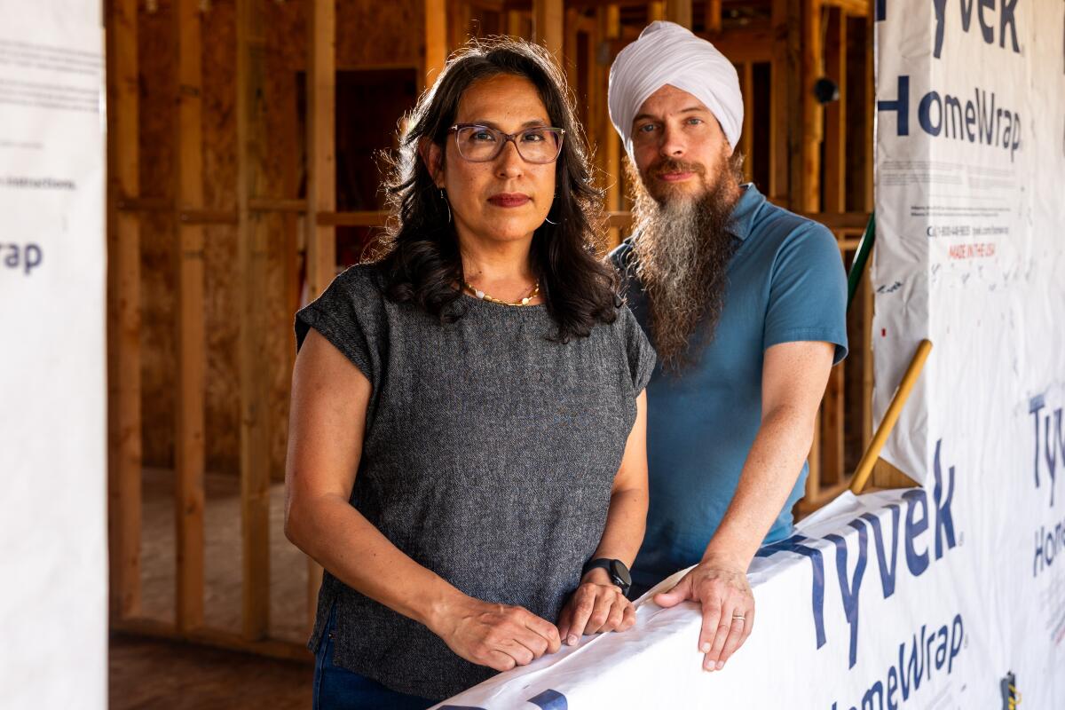 Two people stand in a half built house