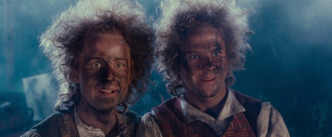 Two light-skinned men with charred faces and hair standing on end.