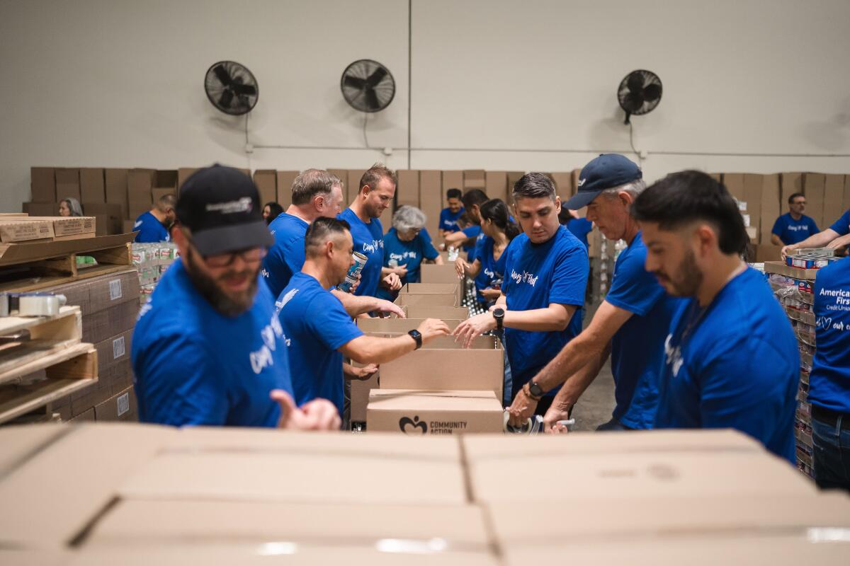 An assembly line of American First Credit Union employees work diligently at the OC Food Bank during a June 23 community day.