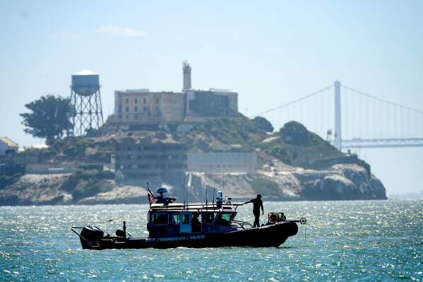 A police boat passes Alcatraz Island as search and rescue operations continue for victims of a Tuesday boat sinking on Wednesday, July 15, 2026, in San Francisco. (AP Photo/Noah Berger)