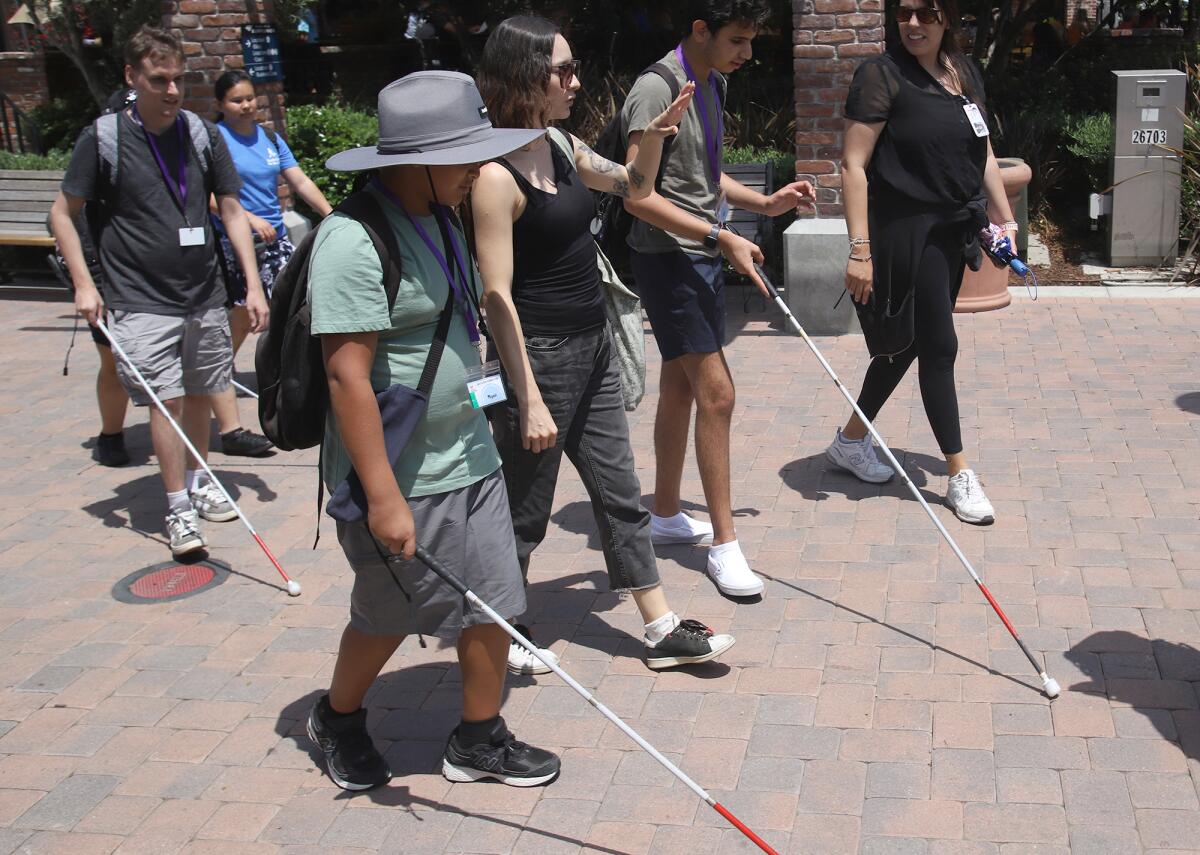 Teens and young adults with visual impairment and other disabilities are guided by a teacher.