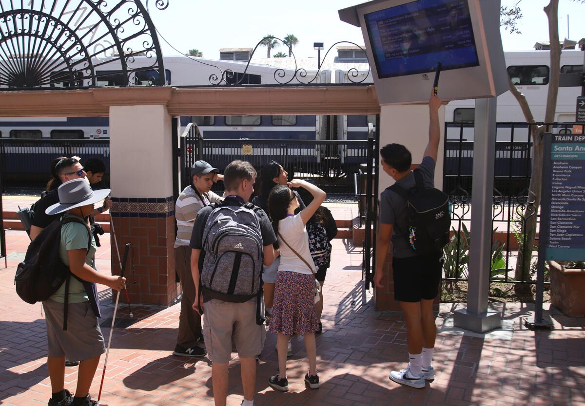 Jacob Garcia, right, a teacher of students with visual impairment, explains how the Amtrak train schedule works.