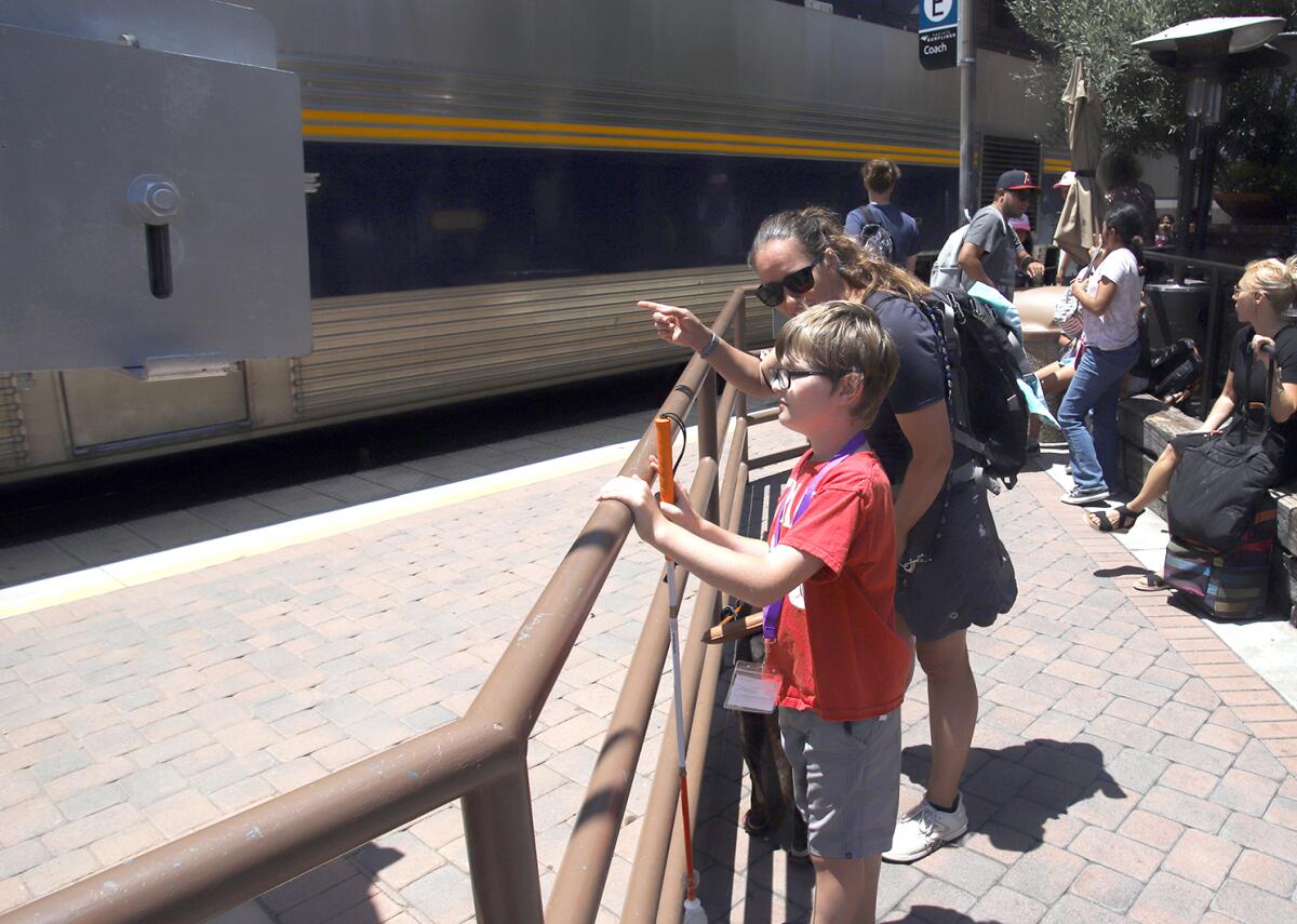 Tank Duffy, 10, is guided by his mother Angie as they listen as the train passes during the Beyond Blindness Next Steps camp.