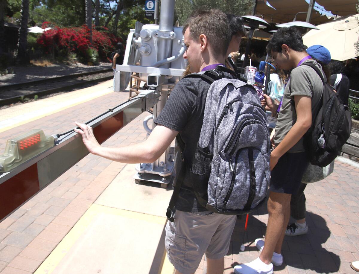 Brandon Reed, 29, a youth enrichment intern who is visually impaired, feels the railroad track gate arm.
