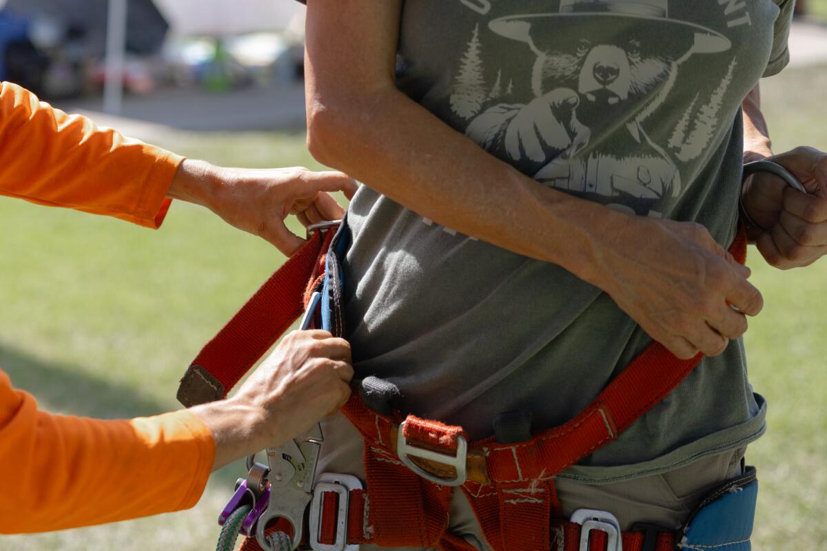 Dey De Guzman helps Sabine Hoppner attach her climbing harness at a community event