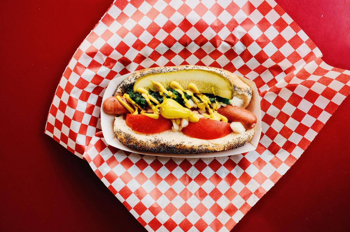 An overhead photo of a Chicago dog atop red-and-white-checkered paper on a red table at Larry's Chili Dog in Burbank.