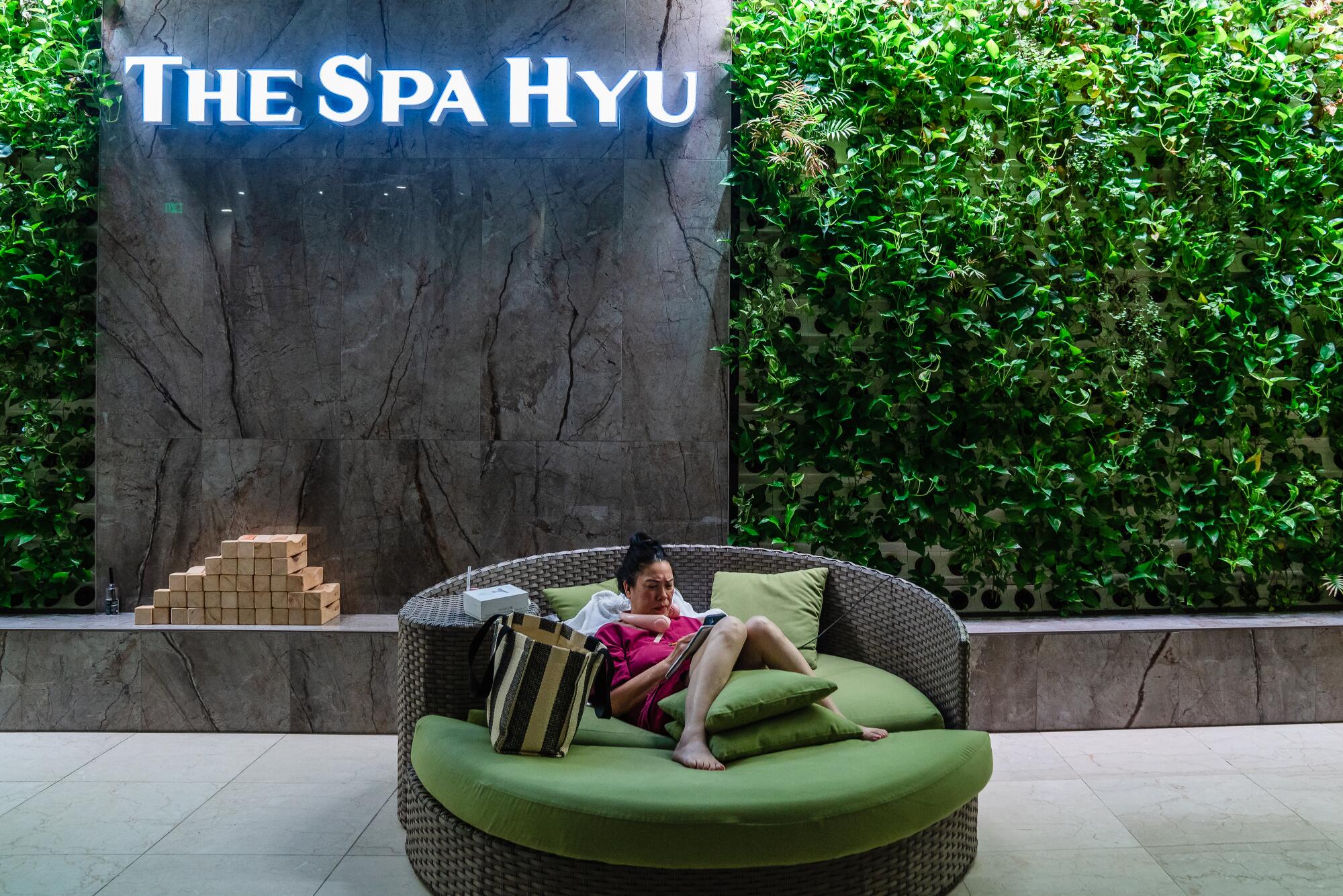 A visitor relaxes by the plant wall, which has about 1,200 pots of living greens.