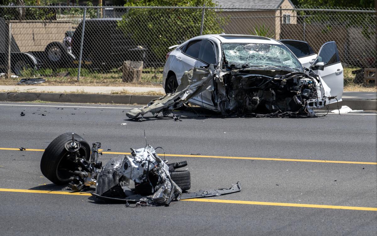 Wreckage is strewn in a street after a vehicle collision.